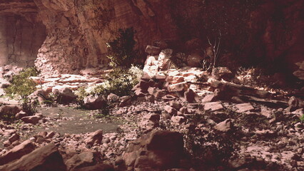Soft light filters through the rocky formations of a cave, highlighting the flowing water and lush greenery. This serene environment invites exploration and tranquility at golden hour.