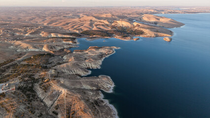Tishrin Dam in Syria. A massive water dam in the desert. High-angle drone shot showing a giant dam structure holding back turquoise river water amid an arid desert landscape, used for water management
