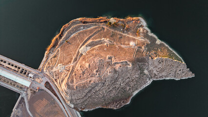Tishrin Dam in Syria. A massive water dam in the desert. High-angle drone shot showing a giant dam structure holding back turquoise river water amid an arid desert landscape, used for water management