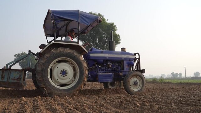 indian farmer working with tractor at agriculture field 