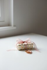 Gift wrapped with pink ribbon on a white table near a window in a bright room
