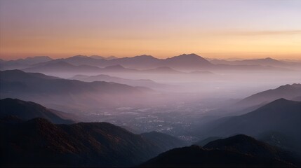 Fototapeta premium Layered mountain ranges shrouded in mist at sunset with a valley below