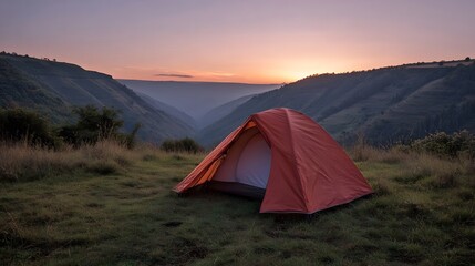 A lone tent is pitched on a grassy hill overlooking a serene valley at sunrise bathed in warm morning light