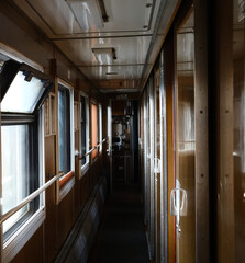 Narrow corridor inside passenger sleeping train with windows and seats