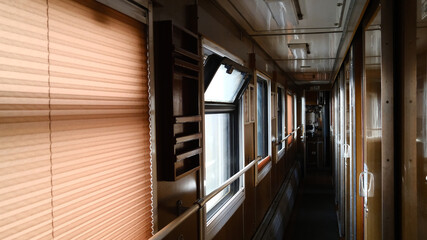 Narrow corridor inside passenger sleeping train with windows and seats