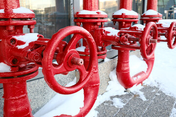 Red industrial gas pipes with valves covered in snow outdoors