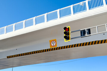 Modern overpass with traffic light and road sign, urban infrastructure, concrete bridge structure against blue sky