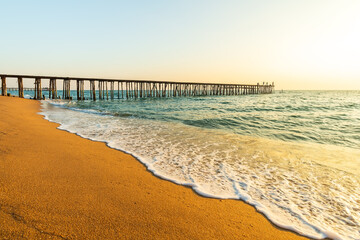 Beautiful seascape and long wooden bridge go to the sea in beautiful tropical island at sunset. Breezy wavy seawater.