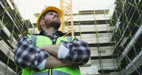 Construction site, thinking and man with inspection, arms crossed and below with planning. Person,...