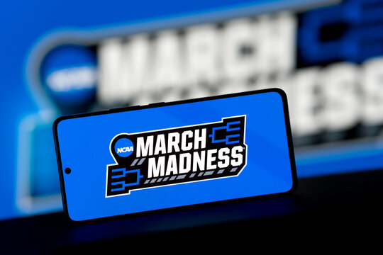 Smartphone displaying the NCAA March Madness logo against a blurred blue background.