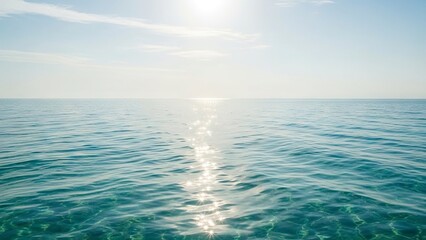 Obraz premium Sundrenched turquoise sea sparkles with light reflections under a pale cloudstreaked sky