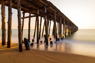 Long wooden bridge go to the sea in beautiful tropical island at sunset.