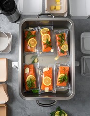 Cooking salmon with herbs and lemon in vacuum bags for meal prep at home with clean kitchen setup