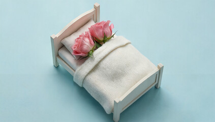 Miniature bed with pink roses on pillows against a pastel blue backdrop