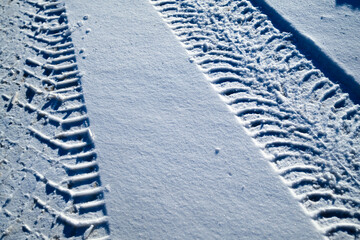 Snow surface with clear tire tracks and strong sunlight shadows