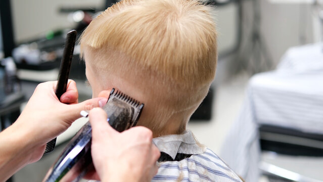 Child getting a haircut with clippers in a barbershop
