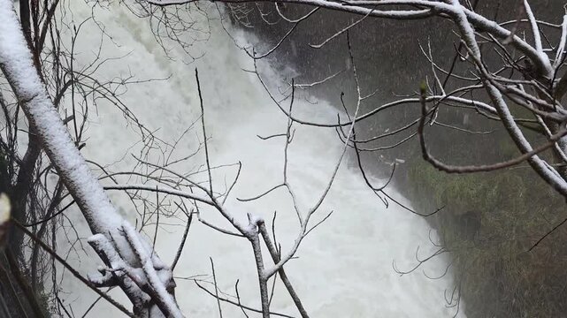 Winter snowfall at Li Vurgacci waterfall in Pioraco, Italy. Scenic frozen river stream and snowy rocks in the Marche region. Picturesque nature landscape in winter