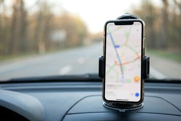 Smart phone with GPS navigation map on screen mounted on car dashboard. Modern automobile technology for travel and trip concept.