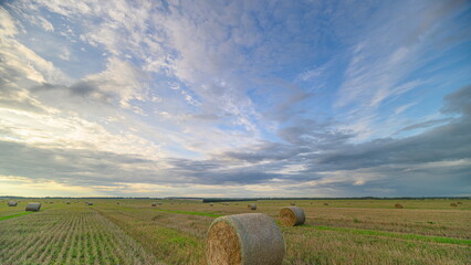 A Serene Landscape Featuring Rolling Hay Bales Beautifully Arranged Under A Dramatic Sky