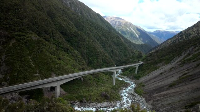 Kea parrot flying away over mountain valley bridge in Arthurs Pass