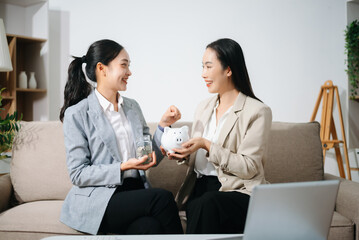 Businesswomen discussing financial planning and saving money using piggy bank at home office. Investment, budget, teamwork, female leadership
