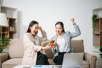 Happy Asian businesswomen celebrating success together at office. Teamwork, collaboration, business achievement, financial growth and positive corporate work concept.