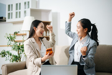 Happy Asian businesswomen celebrating success together at office. Teamwork, collaboration, business achievement, financial growth and positive corporate work concept.