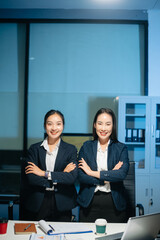 Confident Asian businesswomen smiling and showing thumbs up in modern office. Professional teamwork, success, trust, leadership