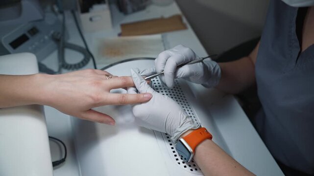 Separating cuticle from nail plate using metal cuticle pusher during manicure process, following technique and hygiene standards
