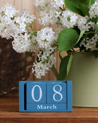 March 8 date block and white lilac flowers