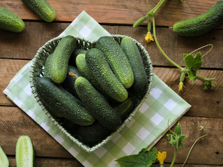 Fresh garden cucumbers in heart shaped basket on wood
