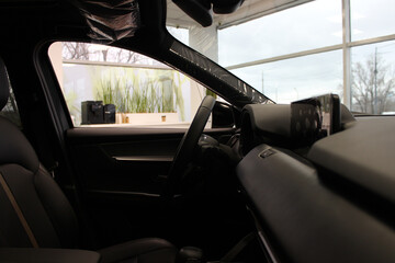 The interior parts of a new car in a dealership showroom is wrapped in protective film

