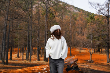 Smiling young woman enjoys the autumn weather in the forest. Autumn landscape.