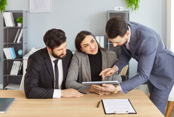 Businesspeople interacting with tablet computer, focusing holding and pointing, discussing company information collaboratively, engaged in business meeting or presentation prepare, consulting