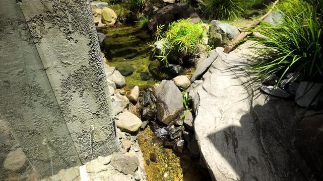 Narrow Creek Between Rocks Beside Rough Concrete Wall