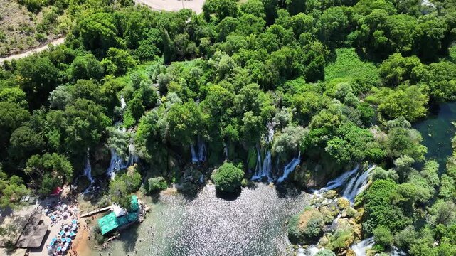 Drone footage of Kravica cascades and swimming zone highlighting flowing water circular pools and lush surroundings from above