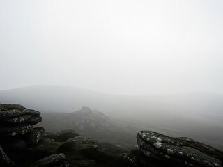 Misty mountain peaks with rocky terrain and dense foggy atmosphere