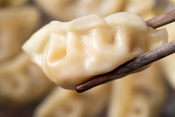 Close up of hot steamed dumpling being picked up by chopsticks in a steamer pot