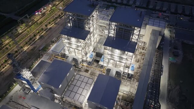 Aerial night view of industrial complex with illuminated buildings and structural details