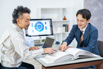 打ち合わせをする作業着、スーツを男性たち