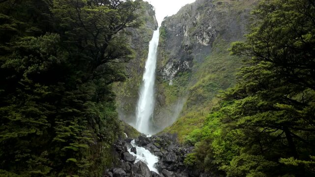 Waterfall view panning from top to bottom through green gorge