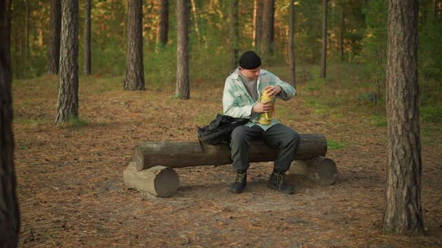 caucasian trekker checking gear on bench pine woods, unwrapping ration and adjusting boots, canteen and map beside backpack, late afternoon light, focused maintenance and survival readiness on trail