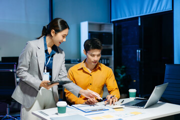 Asian business colleagues collaborating in modern office, using tablet and laptop for planning, consulting, teamwork and digital business strategy.