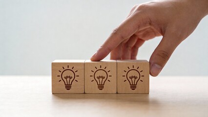 Hand arranging wooden blocks with lightbulb symbols