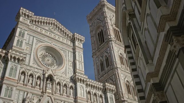 Cathedral facade with rose window and statues, rising tower against blue sky in building; timeless awe.