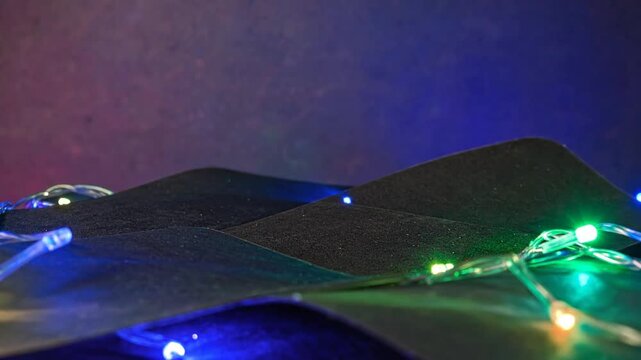 Black abstract shapes with string lights against a gradient purple and blue background