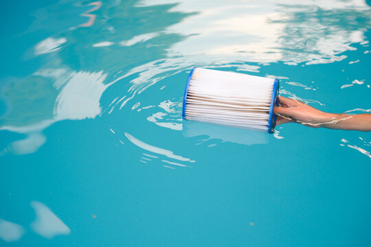 Сhild Playing with Replacement Pool Filter Cartridge in Swimming Pool. Copy space.