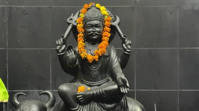 Lord Shani Dev decorated with floral garlands, symbolizing strength, cosmic justice, and spiritual discipline in Hindu worship.