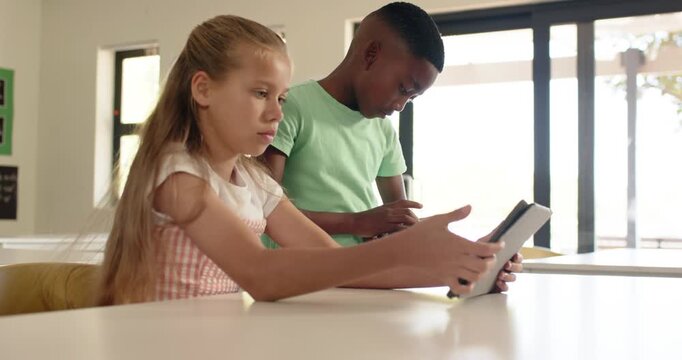 Two youths starting study session, tapping and rotating tablets with keyboard folio at school table