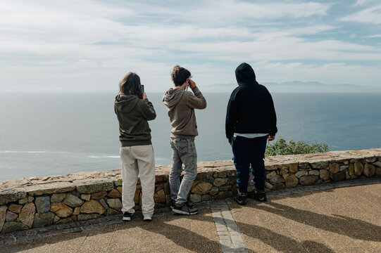 Friends look out at the ocean from a viewpoint during the day